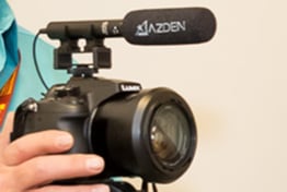 A close-up of a SLR camera with a microphone connected to the top.